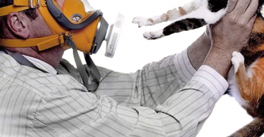 Foto di un uomo che indossa una maschera a GAS e tiene in mano il suo gatto